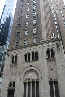 An arched window on 48th Street, divided into four sections. There are windows above and to the right of the arch, as well as a door to the left.