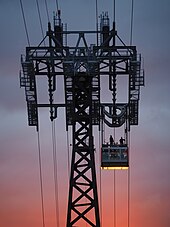 One of the tramway's support towers as seen at dawn. There is a cabin on the wires to the right of the support tower.