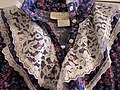 Collar of a 1970s prairie dress, showing common parts of the style such as lace, buttons, floral fabric, and ruffles.