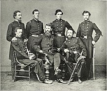 Black and white photo shows seven men in dark military uniforems.