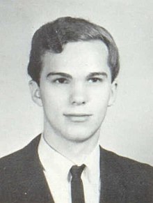 A monochome portrait photograph of a white teenager wearing a collared shirt, tie, and jacket; he is looking to the camera's right with a neutral expression