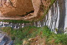 Water slowly seeping from tan porous sandstone at contact with impermeable gray shale creates a refreshing growth of green vegetation in the desert.