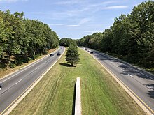 A four-lane limited access parkway lined with trees on the sides and in the median.