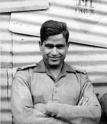 Black and white photograph of a smiling Kirori Singh Bainsla, arms crossed, looking at the camera lens