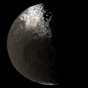 An image of a half-illuminated Iapetus, taken by Cassini on November 12, 2005, from a distance of 417,000 kilometers (259,000 miles) during its flyby of Saturn. The big crater at the center is Turgis, while the partly-shadowed crater with a central peak to the north is Roland.[58]