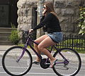 A woman cycling while wearing a sweater and miniskirt in Canada.