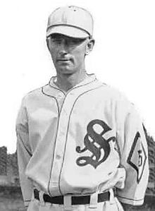 A man in a white baseball jersey with a dark "S" on the chest.