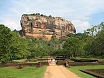 A large granite rock with people walking toward it