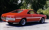 Shows the rear right of a 1969 AMC Javelin SST finished in red with white bodyside C-stripe