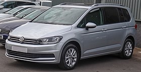 Front-three-quarter view of a five-door car with a raised roofline, flush headlights, door mirrors with integrated turning indicator lights, alloy wheels, and bars for attaching a roof rack