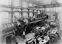 Under assembly c.1890, half of one of the two 10,000 hp engines completed for Deptford Power Station at Hick, Hargreaves and Co.[113][114][115][116] A travelling crane and hoist above.