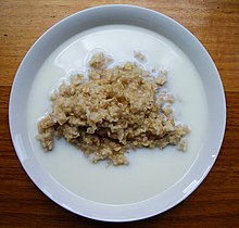 Cooked grain porridge with milk pooling around the edges of the bowl
