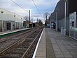 A set of two tram tracks between two platforms with shelters.