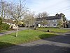 Green area with trees. In the background a terrace of houses.