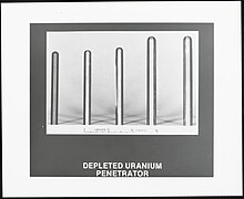 A photographic print of five vertically oriented uranium penetrator rods arranged left to right from shortest to longest. The scale measurement at the bottom shows the width of the rods also increasing in width from left to right from a quarter of an inch to almost half an inch.