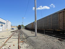 An abandoned railroad station platform with a freight train next to it