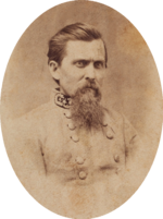 Sepia tone photo shows a frowning man with a beard and dark combed-back hair. He wears a gray uniform with three general's stars on the collar.