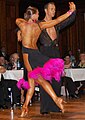 Image 25Latin dancers in their costumes. The woman is wearing backless dress with deep slits on its lower portion, while the man is wearing a shirt with top buttons open. (from Fashion)