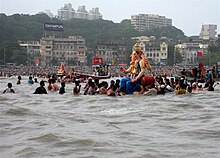 A Ganesha statue on the water, surrounded by people