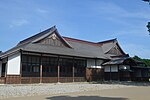 Japanese style wooden building with external covered corridor and white walls.