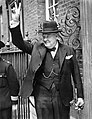 U.K. Prime Minister Winston Churchill in a black lounge suit with homburg hat and walking stick on Downing Street, giving his famous 'V' sign during World War II.
