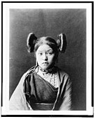 Hopi girl at Walpi, c. 1900, with squash blossom hairstyle indicative of her eligibility for courtship, the squash flower being a symbol of fertility.[52]