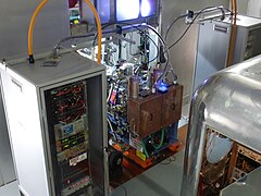 Two ion sources at the center with two high-voltage electronics cabinets next to them[26]