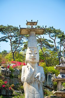 Outdoor, white, Asian statue with tall hat.