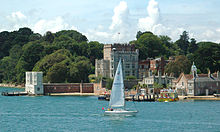 A modern photograph of an island with a yacht in the foreground