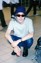 A color photograph of James Iha, who is staring into a fan's camera while holding a can of soda.