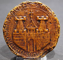 一枚圓形印章，描繪了一座城鎮的城牆，城牆上有兩座塔樓和一座城門，以及一座教堂的塔樓