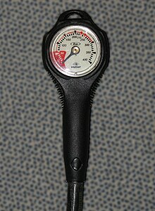 A pressure gauge with a rubber protective housing and flexible high-pressure hose which would be connected to the high-pressure port of the regulator first stage, so that the internal pressure of a diving cylinder can be monitored throughout a dive. The low-pressure area of the face is coloured red to indicate that the pressure may be too low to safely continue diving.