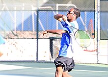 Male player swinging a tennis racquet on a tennis court