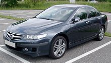 A blue saloon car parked in a bay in an empty car park. The licence plate is blank.