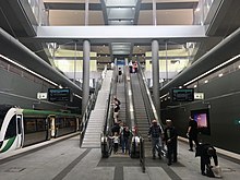 Underground station platform with escalators and stairs in front and a train to the left