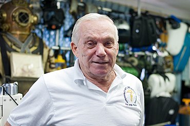 Rutkowski in white T-shirt standing in front of dive equipment