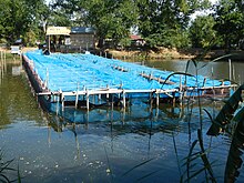 A large rectangular bamboo structure covered with blue nets