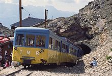 mountain railway train emerging from a tunnel