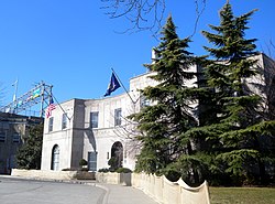 A two-story stone building with trees in front