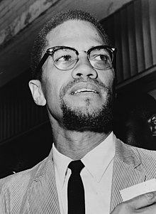 Photograph of Malcolm X smiling and wearing a suit