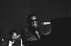 A dark-skinned man wearing dark glasses playing the piano