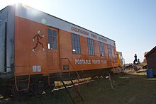 An orange-and-white painted metal railroad boxcar.