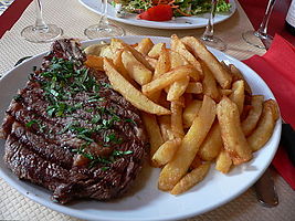 A rib steak, grilled on a griddle and served with French fries