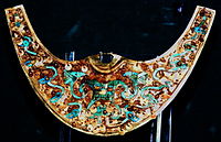 Moche Nariguera depicting the Decapitator (Ayapec, Ai Apaec), gold with turquoise and chrysocolla inlays, c. 200–850 CE, Museo Oro del Peru, Lima