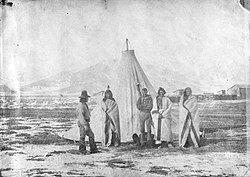 A Group of Utah Indians, including Arrapene (Sinnearoach), the head chief of the tribe, and Luke, the interpreter, taken on the outskirts of Camp Floyd, looking north west towards the Oquirrah Mountains.