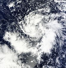 Image of a loosely defined tropical cyclone over open water; while clouds are in a spiral form they are very loose and not bunched together.
