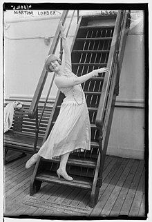 Young woman posing with arms and legs extended, near stairs.