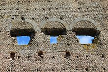 Close-up of a straight row of holes in an ancient wall.