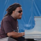 Side view of a man with long hair and sunglasses playing the piano