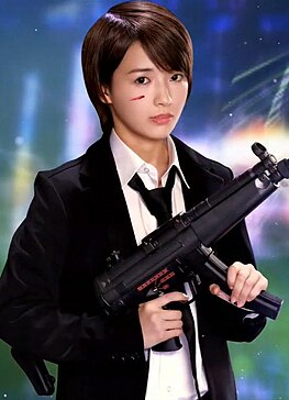 A 2020 photograph of Ai Mukai, posing with a gun as promotion for a video game